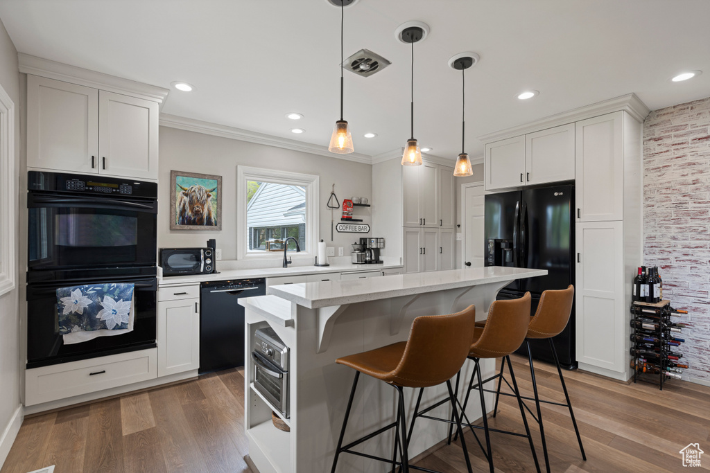 Kitchen featuring hardwood / wood-style flooring, black appliances, and white cabinetry