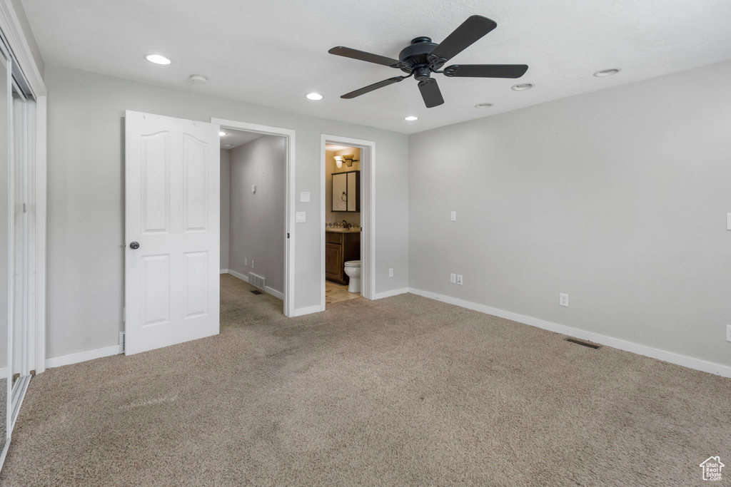 Unfurnished bedroom featuring connected bathroom, ceiling fan, and carpet
