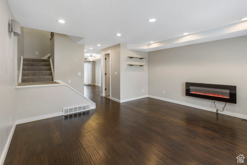 Unfurnished living room featuring dark wood-type flooring