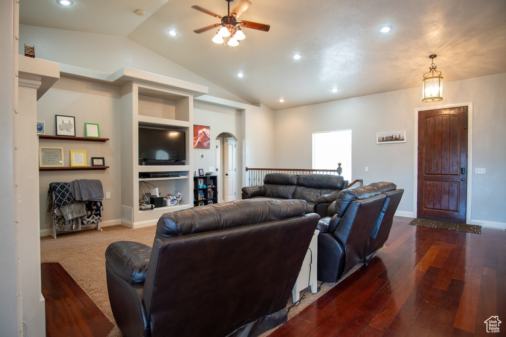 Living room featuring vaulted ceiling, hardwood / wood-style floors, ceiling fan, and built in features