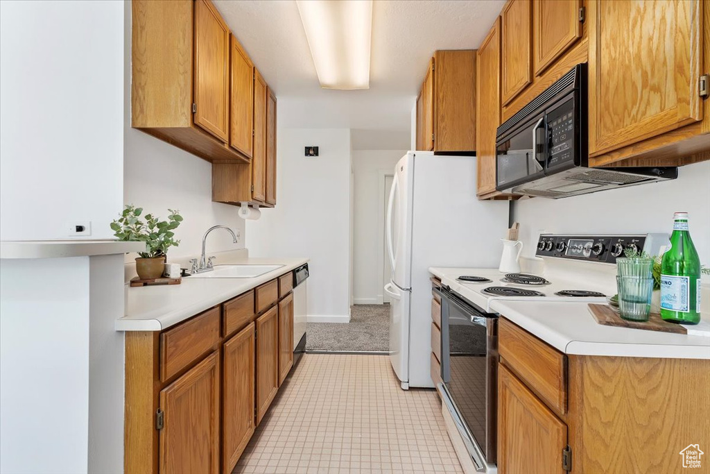 Kitchen with light tile flooring, stainless steel dishwasher, sink, and white electric range