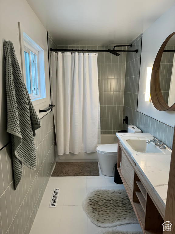 Bathroom featuring tile walls, toilet, tile flooring, and vanity