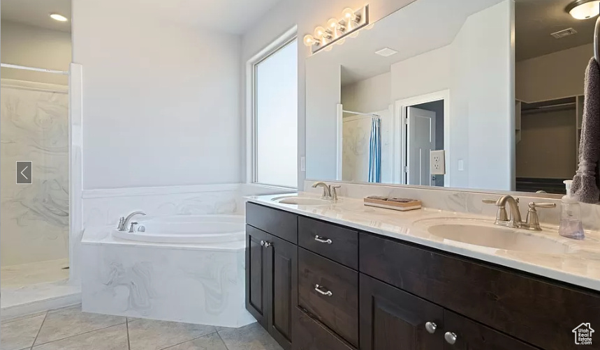 Bathroom with double sink, oversized vanity, tile flooring, and independent shower and bath