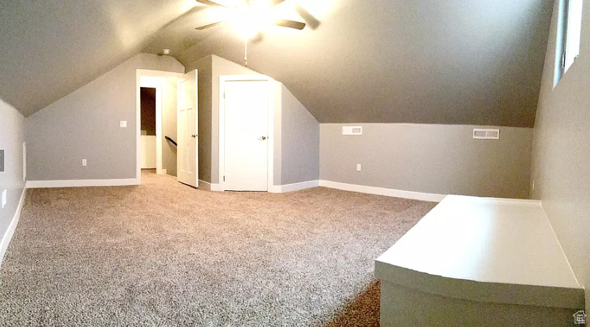 Additional living space featuring vaulted ceiling, ceiling fan, and carpet