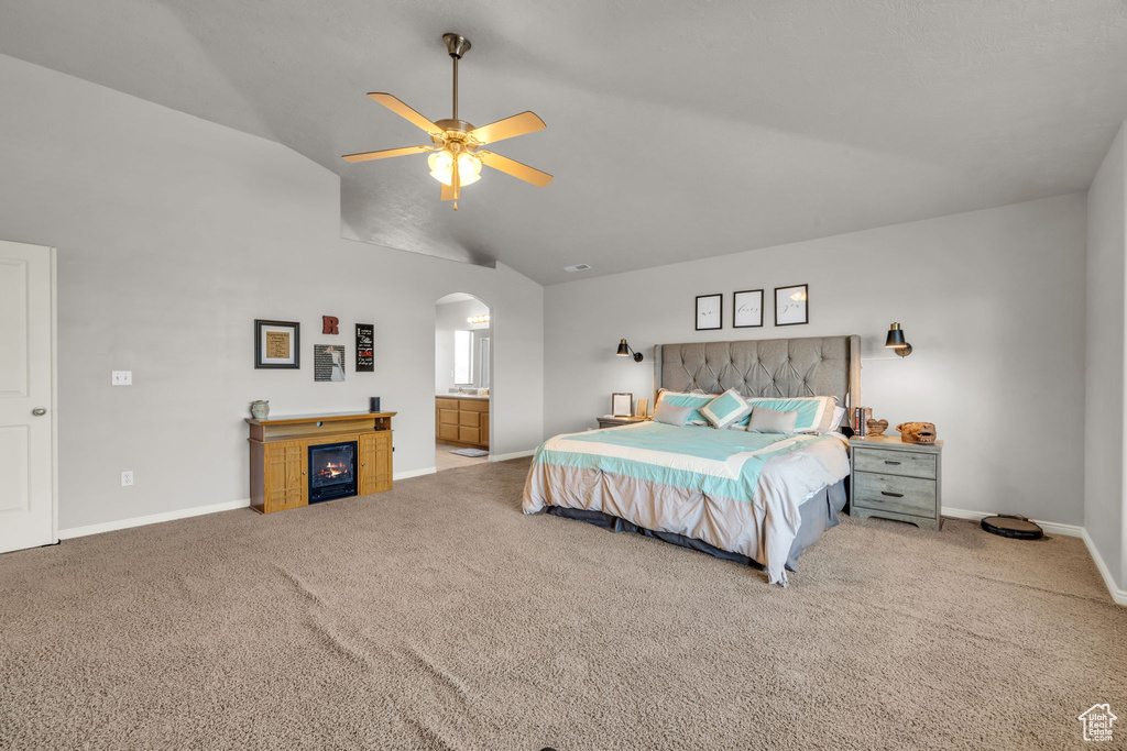 Bedroom with light carpet, high vaulted ceiling, ceiling fan, and ensuite bathroom