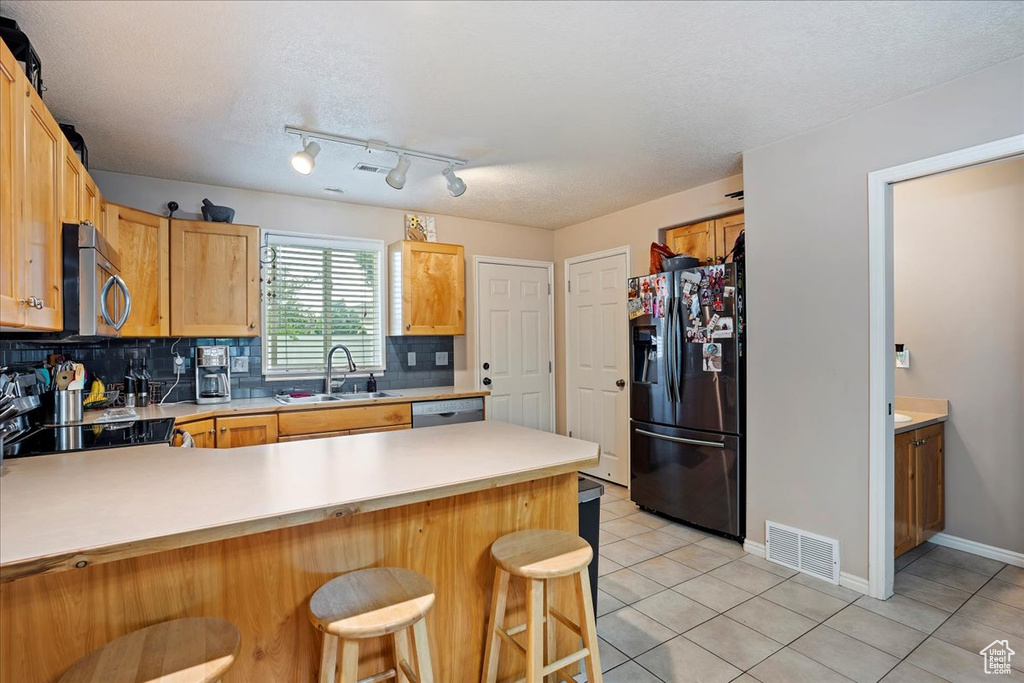 Kitchen with appliances with stainless steel finishes, light tile floors, sink, tasteful backsplash, and rail lighting