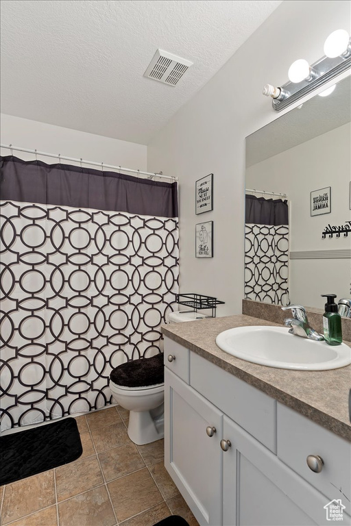 Bathroom with tile floors, toilet, oversized vanity, and a textured ceiling