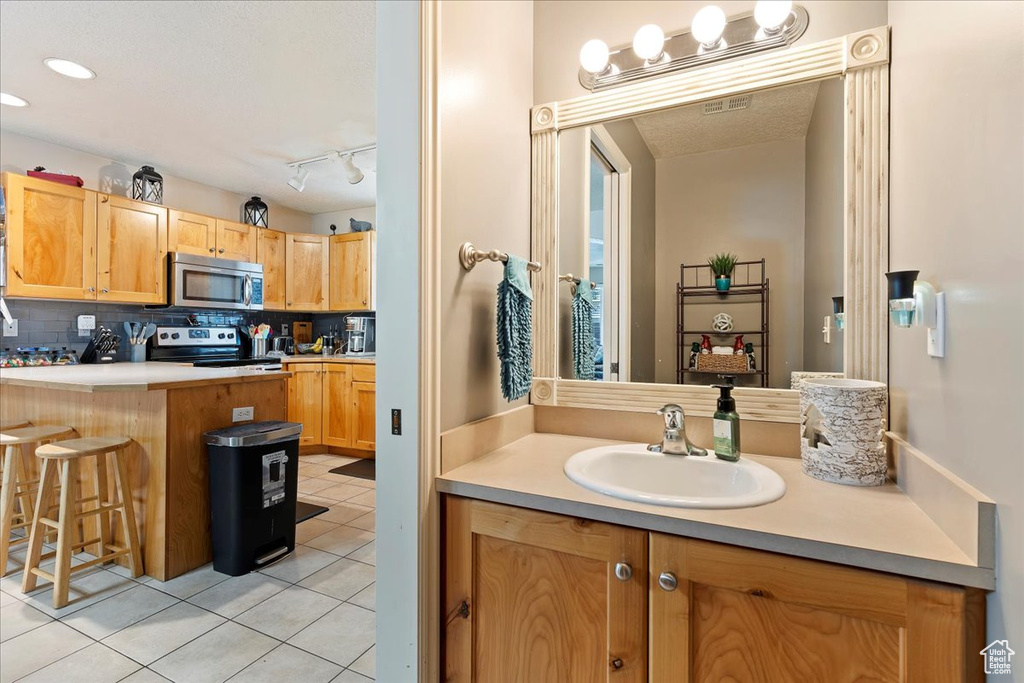 Bathroom with sink, tasteful backsplash, rail lighting, and tile floors