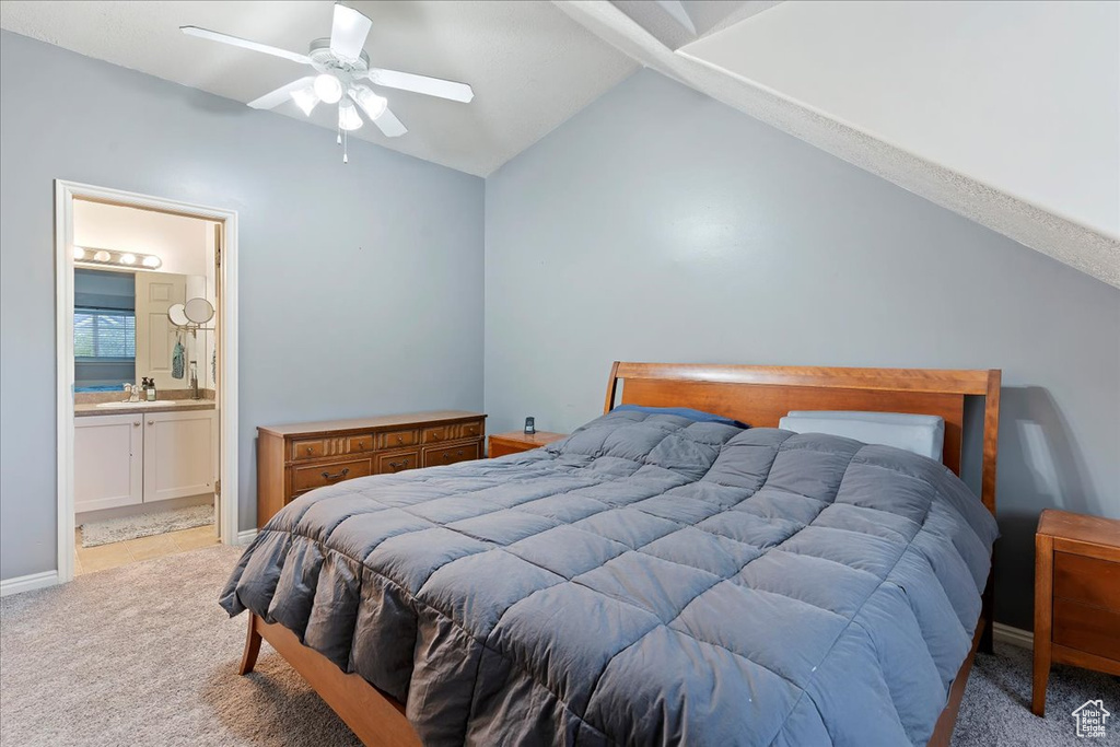 Bedroom with ceiling fan, light carpet, sink, connected bathroom, and lofted ceiling