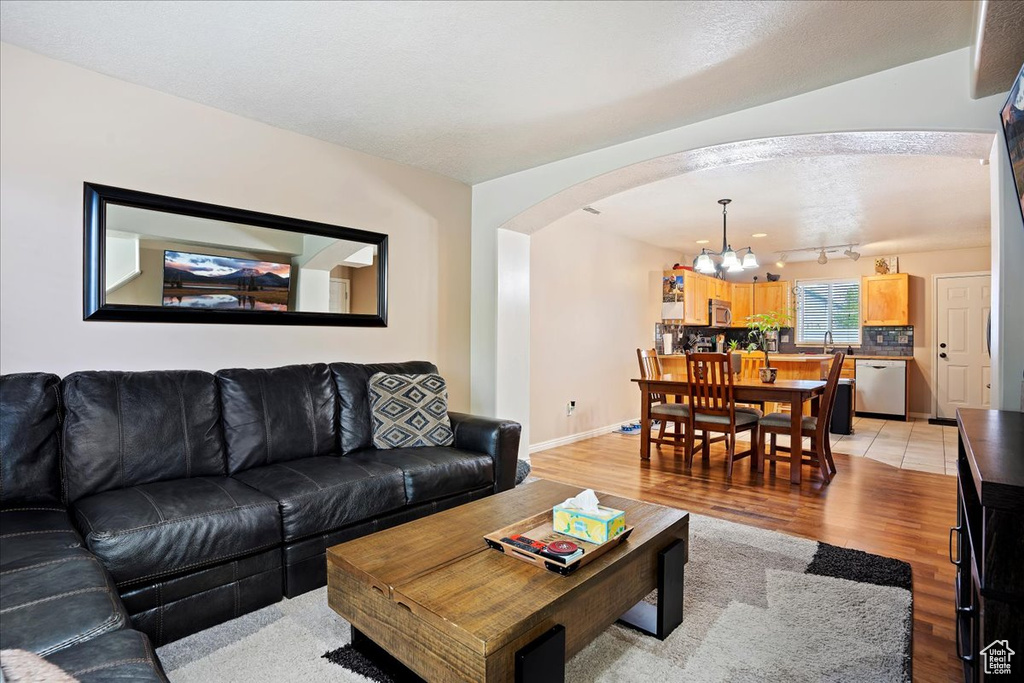 Living room with a chandelier, light wood-type flooring, and track lighting