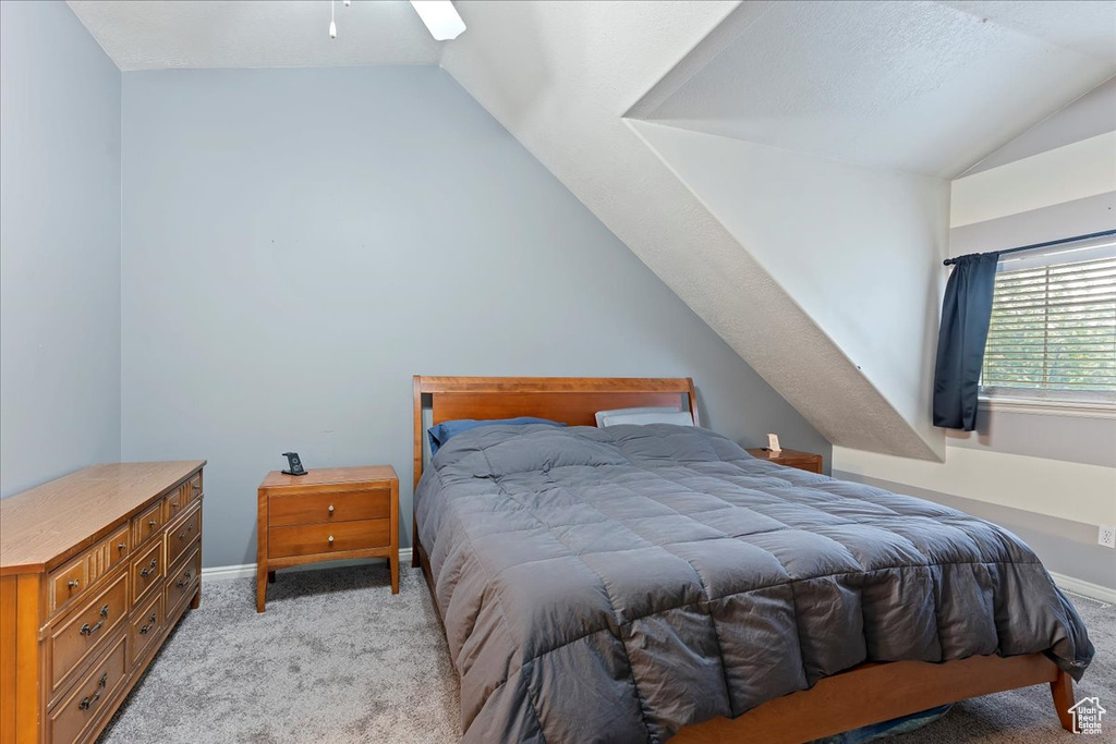 Carpeted bedroom with lofted ceiling and ceiling fan