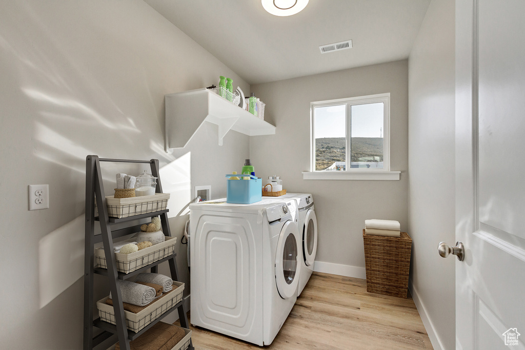 Laundry room with washing machine and dryer, light hardwood / wood-style floors, and washer hookup