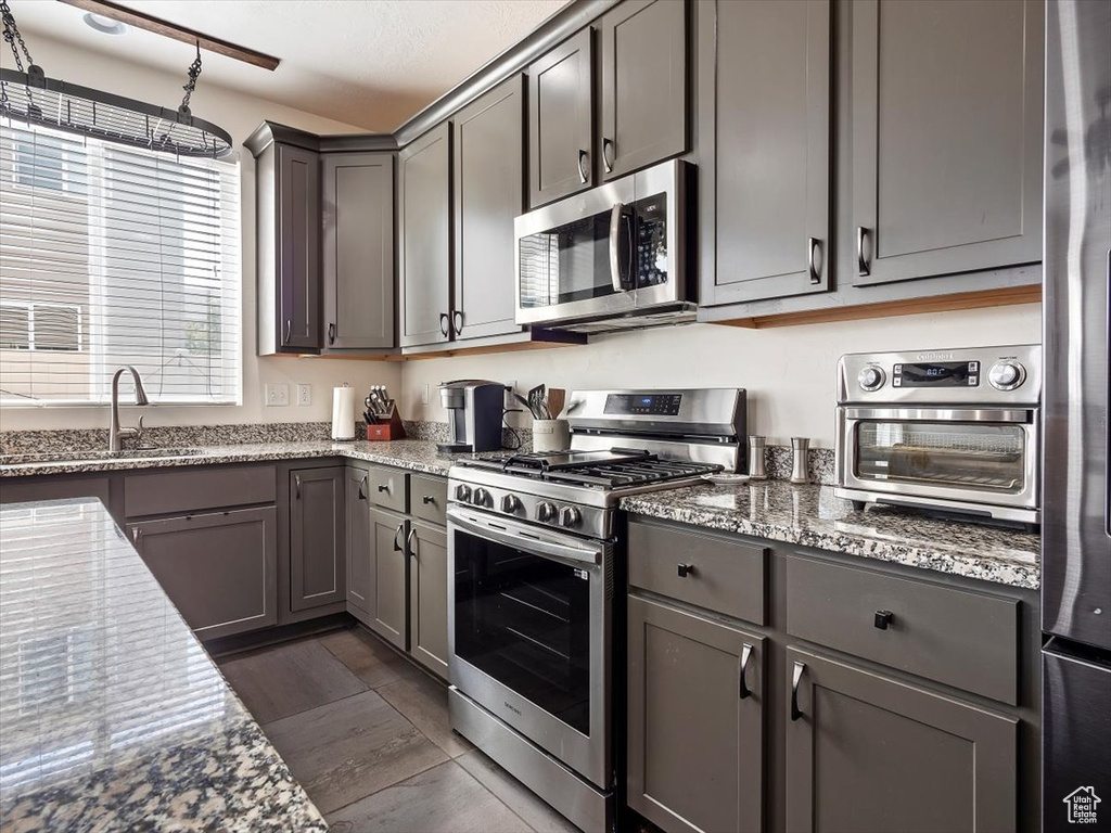 Kitchen with sink, appliances with stainless steel finishes, dark hardwood / wood-style floors, and stone countertops