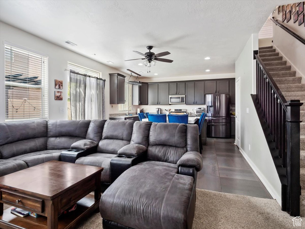 Living room featuring sink, ceiling fan, and dark tile floors