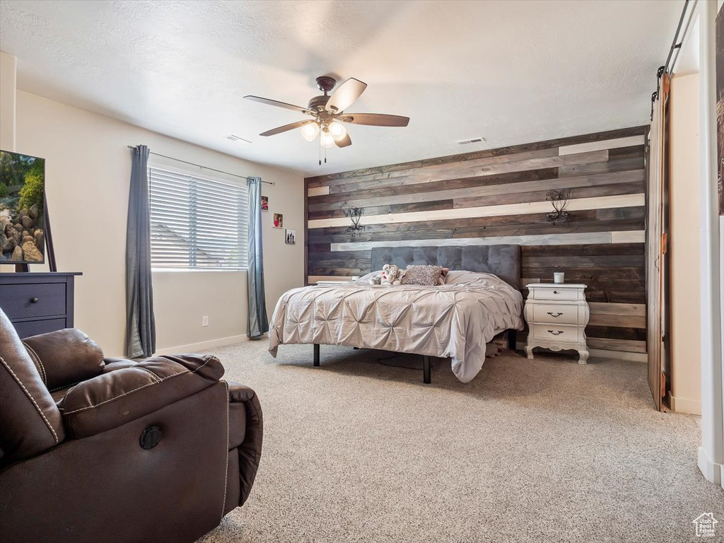 Bedroom featuring wood walls, ceiling fan, and carpet flooring