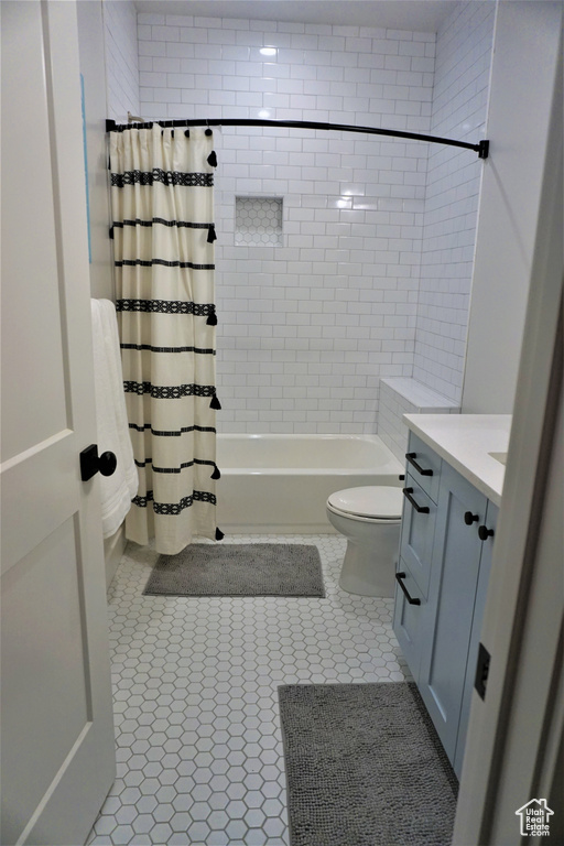 Full bathroom with tile flooring, vanity, toilet, and shower / tub combo with curtain