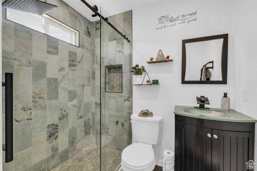 Bathroom featuring a shower with door, toilet, and vanity