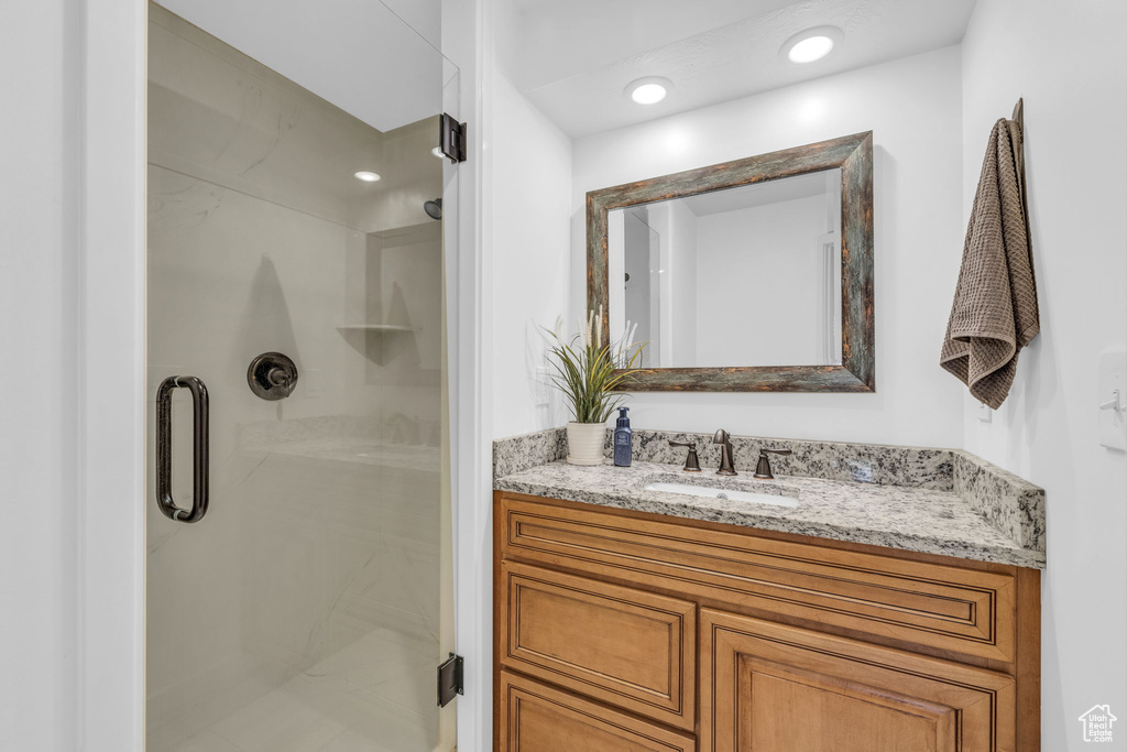 Bathroom featuring a shower with shower door and vanity