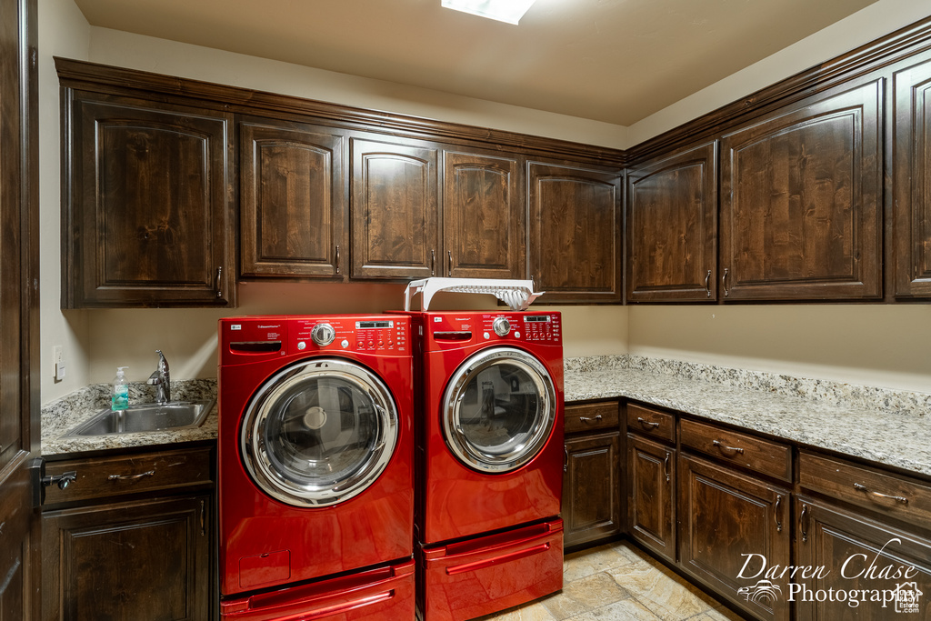 Laundry room with light tile flooring, washer and dryer, cabinets, and sink