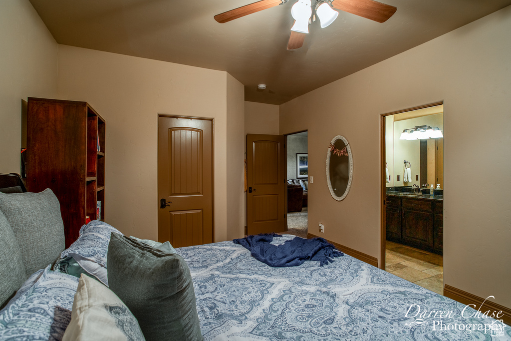 Bedroom featuring ensuite bath, sink, ceiling fan, and light tile floors