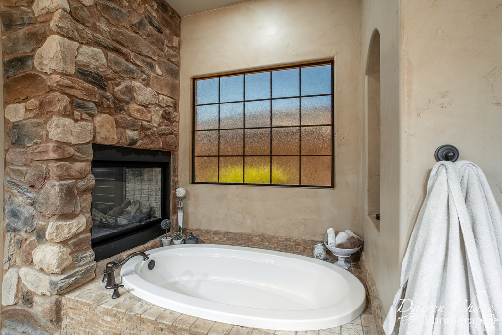 Bathroom featuring a stone fireplace and a bath to relax in
