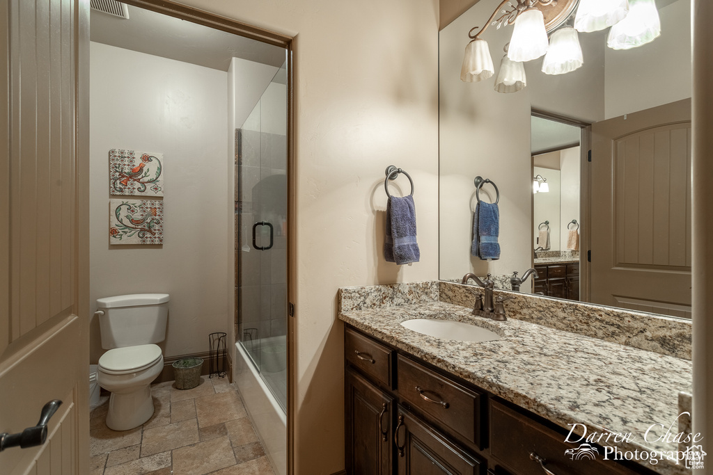Full bathroom with vanity with extensive cabinet space, tile floors, toilet, and enclosed tub / shower combo