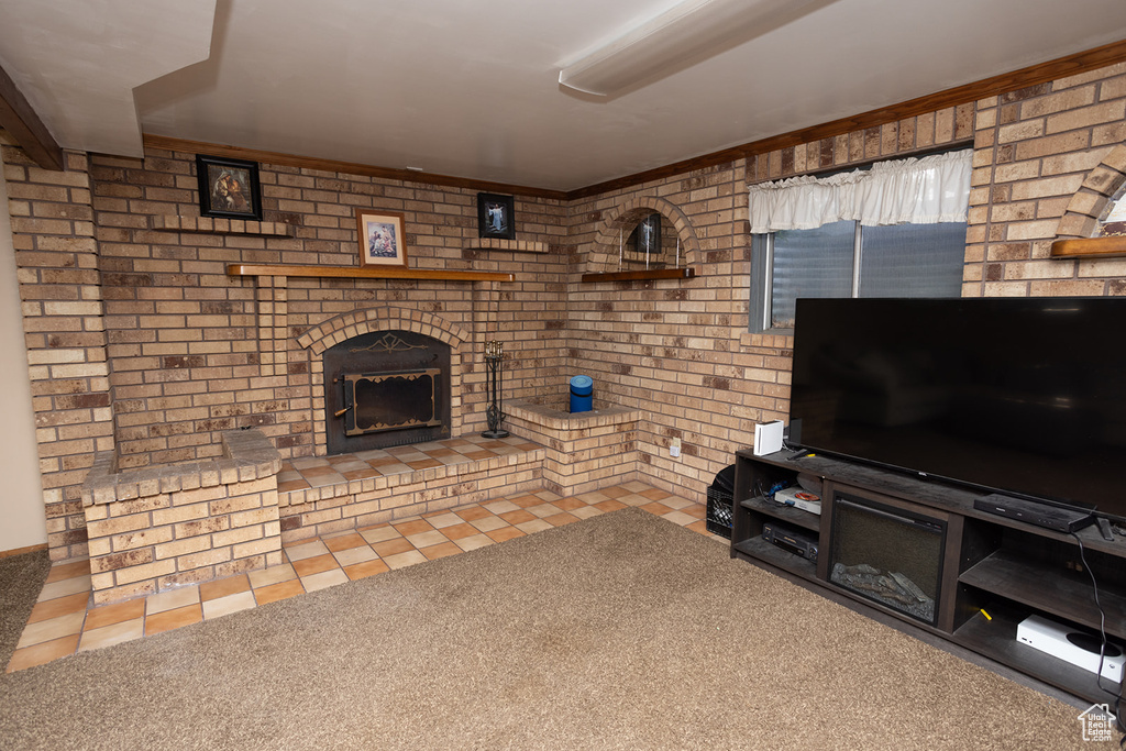 Unfurnished living room with carpet, brick wall, and a brick fireplace