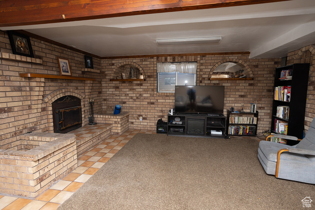 Tiled living room with brick wall, beamed ceiling, and a fireplace