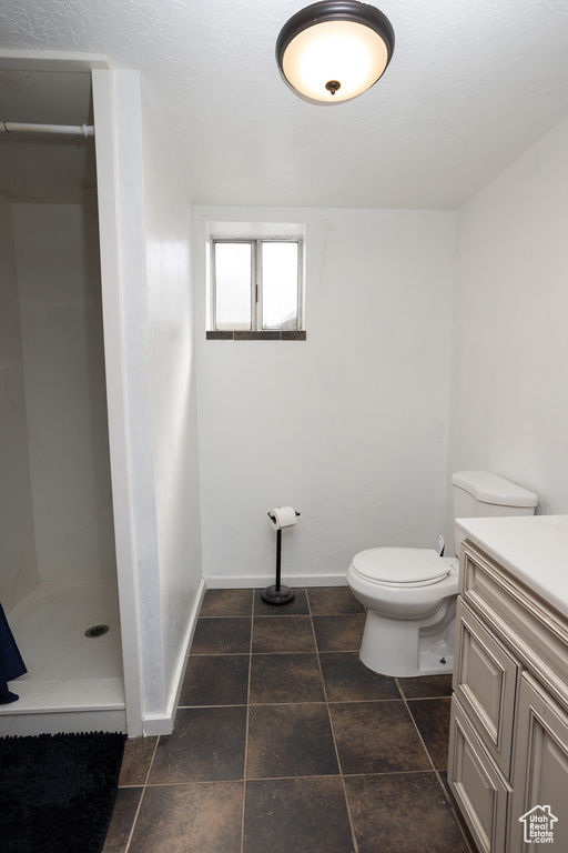 Bathroom featuring tile flooring, a shower, vanity, and toilet