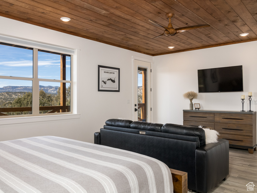 Bedroom featuring a mountain view, light hardwood / wood-style flooring, ceiling fan, and wood ceiling