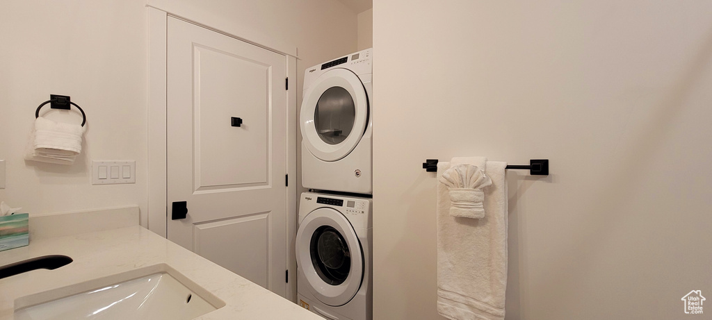 Clothes washing area featuring sink and stacked washer and dryer