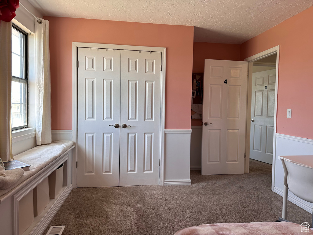 Unfurnished bedroom featuring a closet, carpet floors, and a textured ceiling
