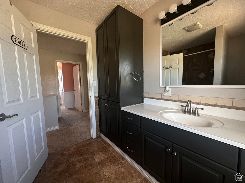 Bathroom featuring a textured ceiling, vanity, and tile flooring