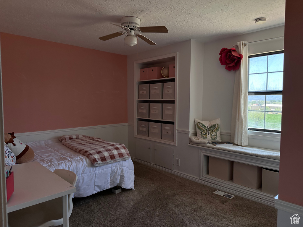 Bedroom featuring ceiling fan, carpet flooring, and a textured ceiling