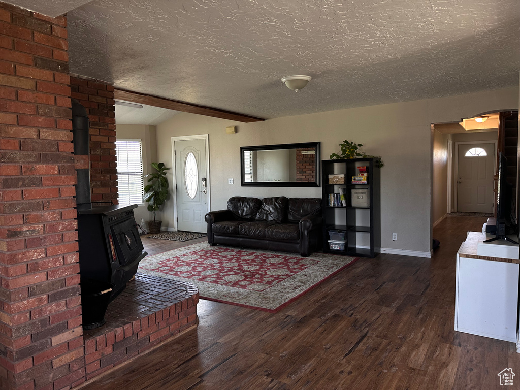 Living room with brick wall, dark hardwood / wood-style floors, and a textured ceiling