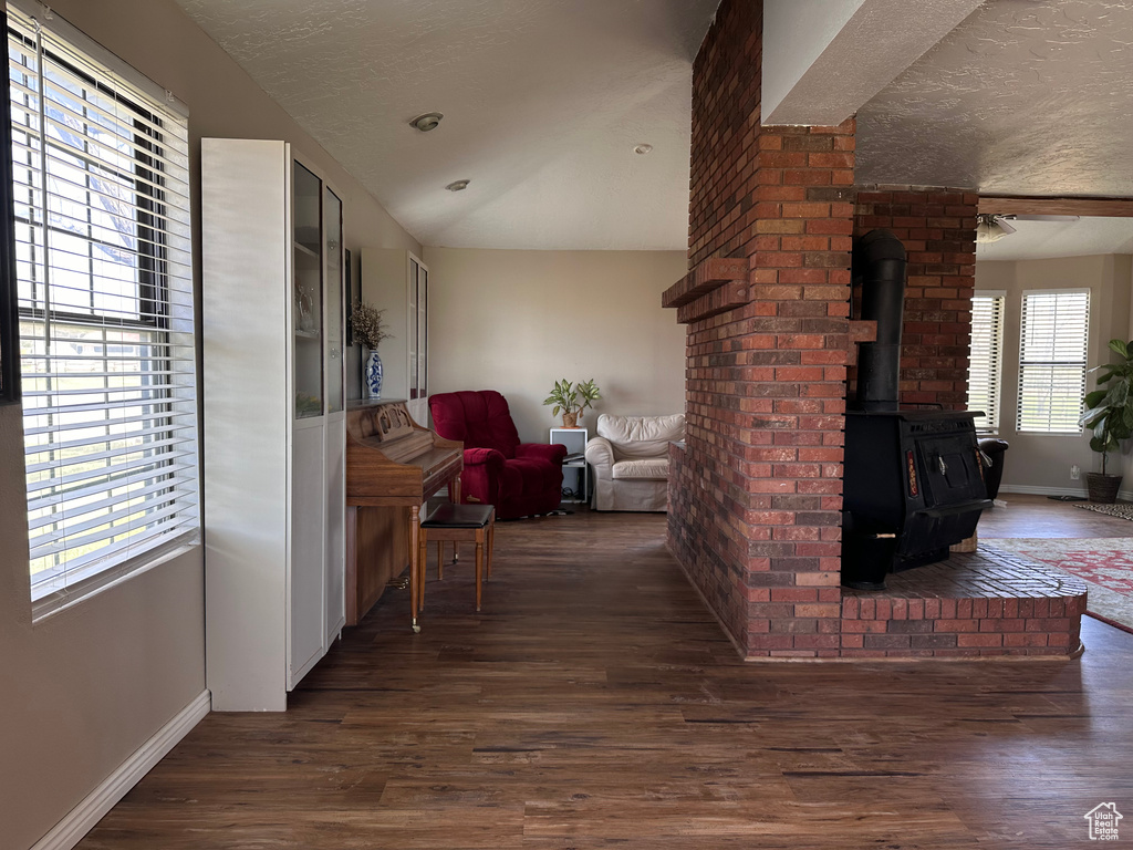 Living room featuring dark hardwood / wood-style flooring, brick wall, a wood stove, and a textured ceiling