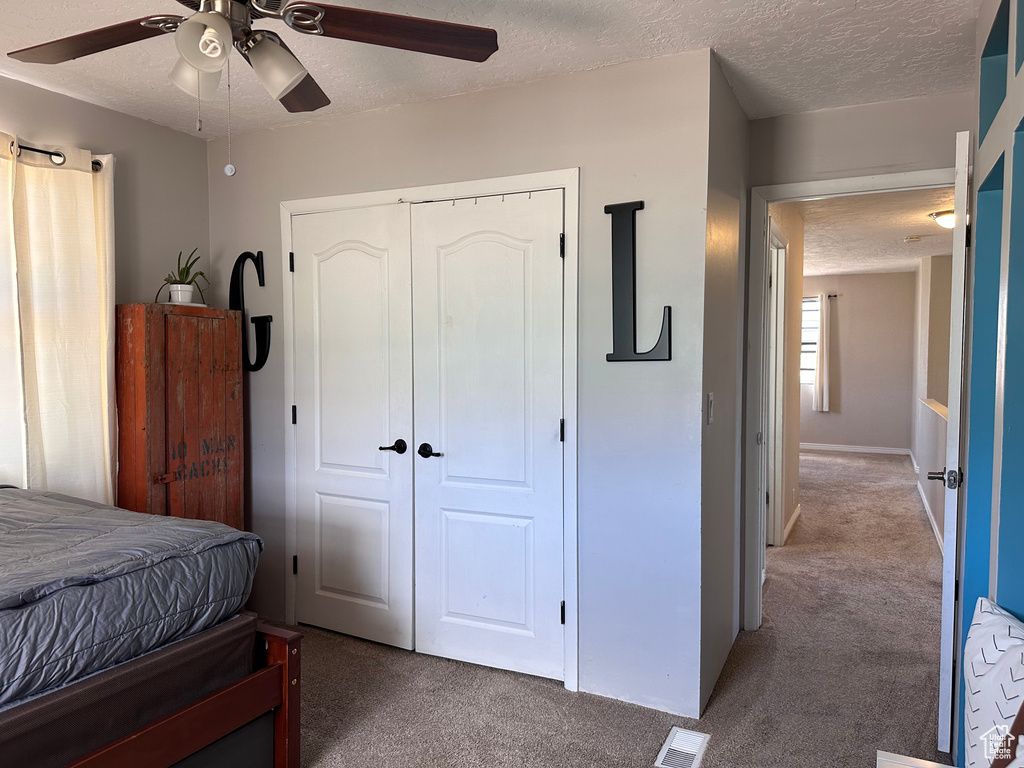 Bedroom featuring a closet, ceiling fan, carpet, and a textured ceiling