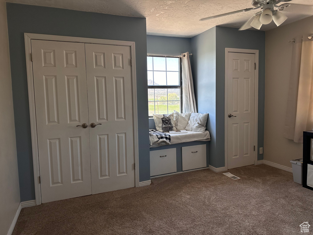 Bedroom featuring ceiling fan, carpet, and a textured ceiling