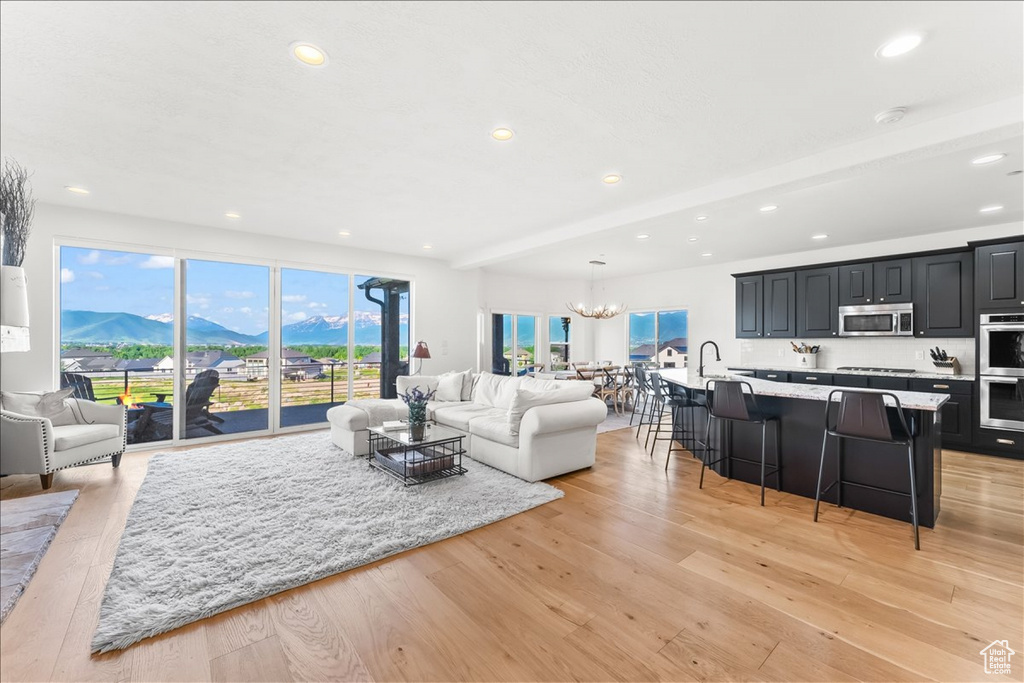 Living room with light hardwood / wood-style flooring, beam ceiling, a mountain view, and a notable chandelier