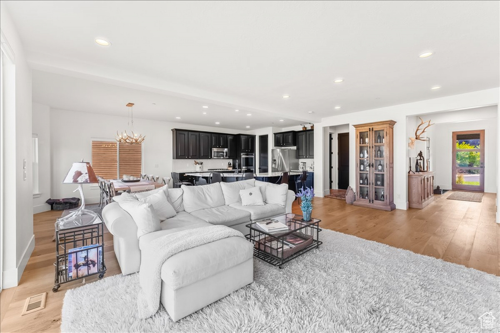 Living room with a notable chandelier and light hardwood / wood-style flooring