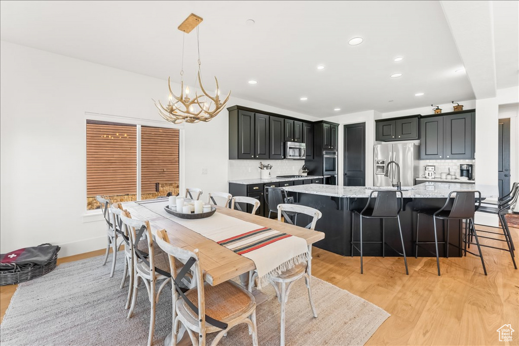 Dining area featuring sink, light hardwood / wood-style floors, and a notable chandelier