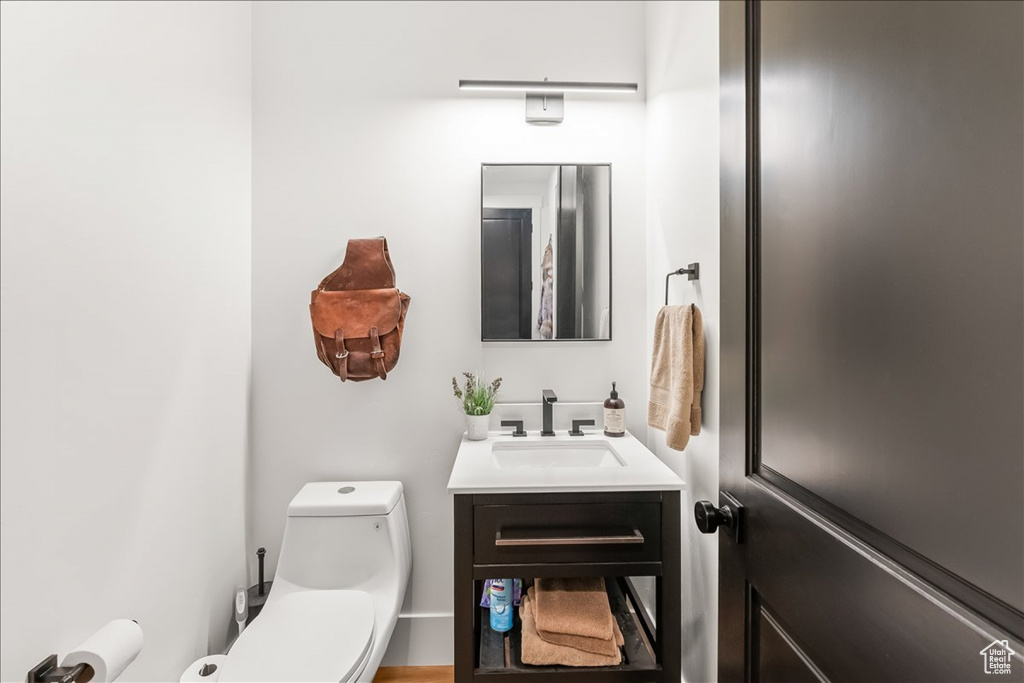 Bathroom featuring vanity with extensive cabinet space and toilet