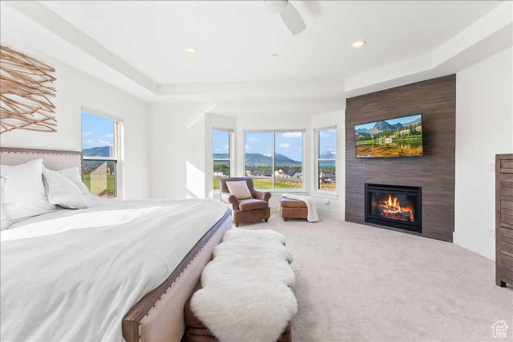 Carpeted bedroom with a large fireplace and ceiling fan