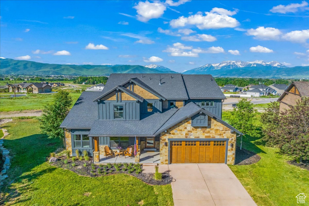 View of front of property featuring a garage, a mountain view, and a front yard