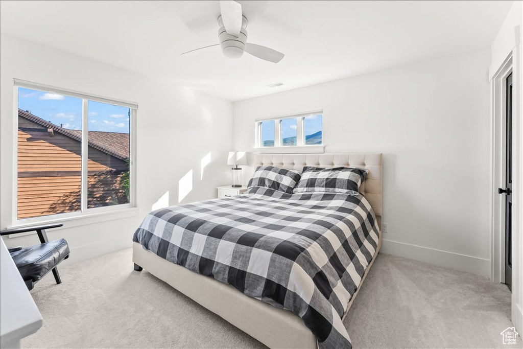 Bedroom with ceiling fan, carpet floors, and multiple windows