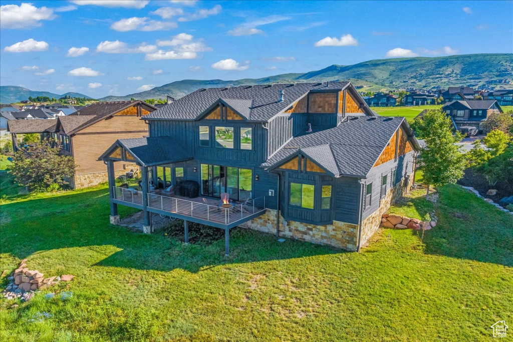 Back of property with a mountain view and a lawn