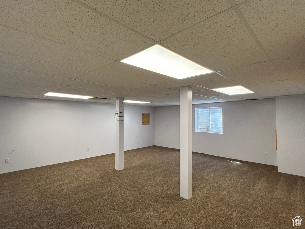 Basement featuring dark colored carpet and a paneled ceiling