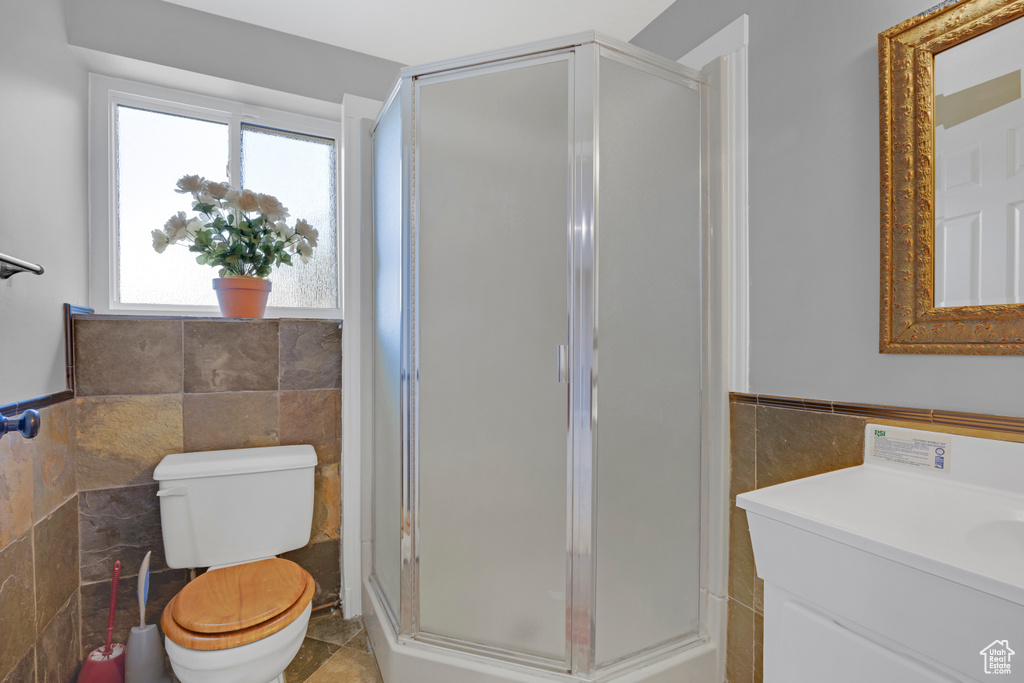 Bathroom featuring vanity, tile walls, a shower with shower door, tile flooring, and toilet