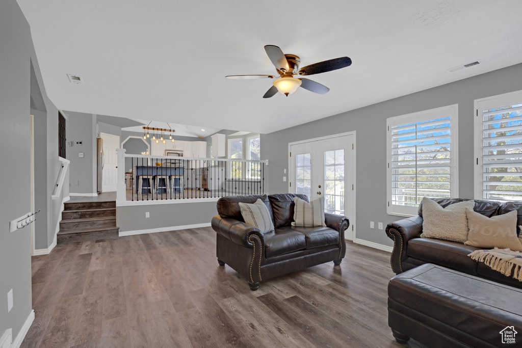 Living room with dark hardwood / wood-style flooring and ceiling fan with notable chandelier