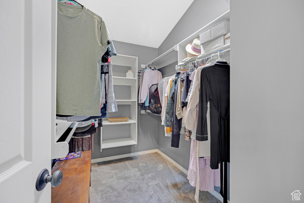 Walk in closet with vaulted ceiling and carpet flooring